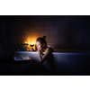 Young woman taking a bath, drinking red wine, enjoying a movie, relaxing after busy work day