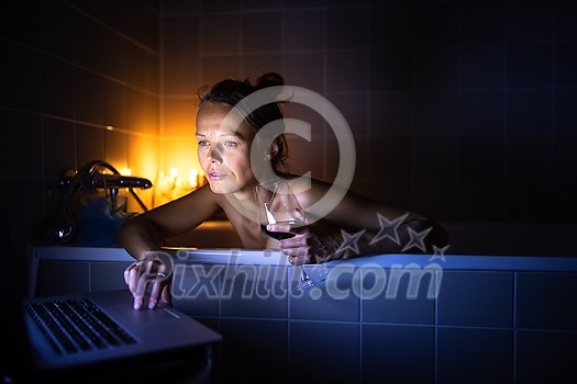 Young woman taking a bath, drinking red wine, enjoying a movie, relaxing after busy work day Young woman taking a bath, drinking red wine, enjoying a movie, relaxing after busy work day