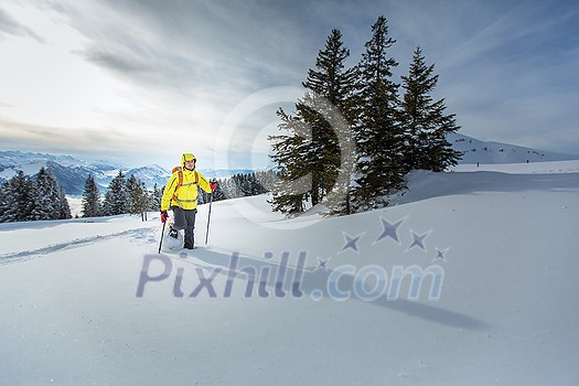 Young man snowshoeing in high mountains, enjoying splendid winter weather with abundance of snow Young man snowshoeing in high mountains, enjoying splendid winter weather with abundance of snow