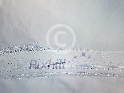 Cross-country skiing: young woman cross-country skiing on a winter day (motion blurred image) - aerial image