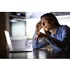 Pretty, middle-aged woman working late in the day on a laptop computer at home, running a business from home/working remotely for a corporation