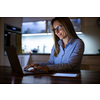 Pretty, middle-aged woman working late in the day on a laptop computer at home, running a business from home