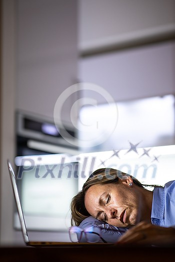 Pretty, middle-aged woman working late in the day on a laptop computer at home, running a business from home/working remotely for a corporation Pretty, middle-aged woman working late in the day on a laptop computer at home, running a business from home/working remotely for a corporation