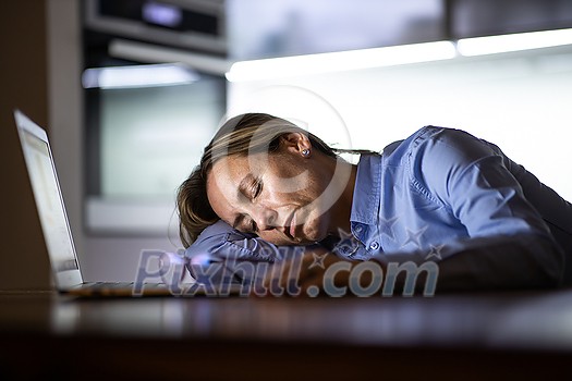 Middle-aged woman working late in the day on a laptop computer at home, running a business from home/working remotely for a corporation Middle-aged woman working late in the day on a laptop computer at home, running a business from home/working remotely for a corporation