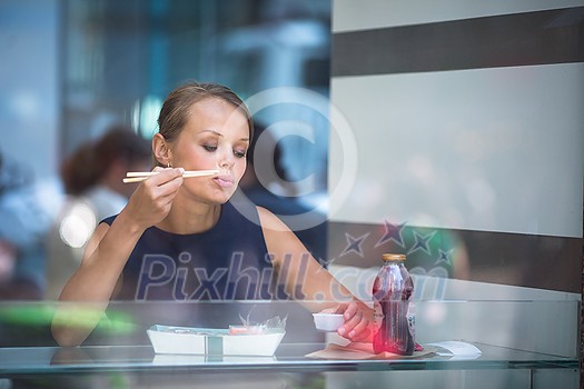Pretty, young woman eating sushi in a restaurant, having her lunch break, enjoying the food, pausing for a while from her busy corporate/office life (color toned image)