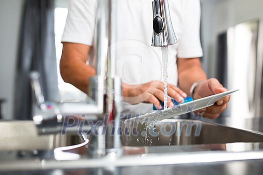 Senior man washing dishes in his modern, bright kitchen Senior man washing dishes in his modern, bright kitchen