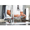 Senior man washing dishes in his modern, bright kitchen