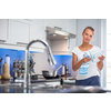 Pretty, young woman in her modern, clean and bright kitchen, fixing lunch (color toned imagey; shallow DOF)