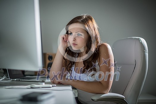 Young woman working on a computer in a home office Young woman working on a computer in a home office