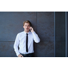 startup businessman in a white shirt with a black tie using mobile phone while standing in front of gray wall during break from work outside