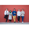 multiethnic group of casual business people using mobile phone during coffee break from work in front of pink wall outside