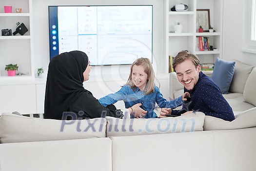 Happy Muslim family with daughter woman in traditional fashionable dress having fun and good time together while sitting on sofa during the month of Ramadan at modern home Happy Muslim family with daughter woman in traditional fashionable dress having fun and good time together while sitting on sofa during the month of Ramadan at modern home
