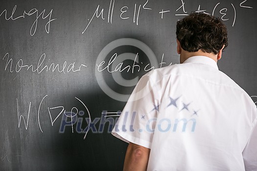 Senior math teacher teaching mathematics, writing on the blackboard during class Senior math teacher teaching mathematics, writing on the blackboard during class