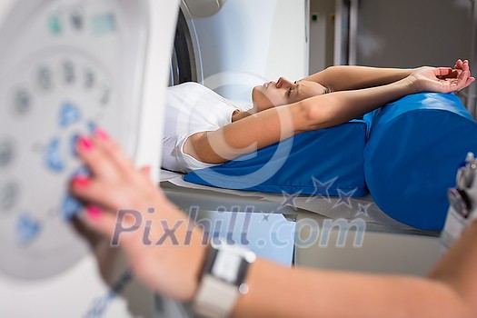Pretty, young woman going through a Computerized Axial Tomography (CAT) Scan medical test/examination in a modern hospital (color toned image; shallow DOF) Pretty, young woman going through a Computerized Axial Tomography (CAT) Scan medical test/examination in a modern hospital (color toned image; shallow DOF)