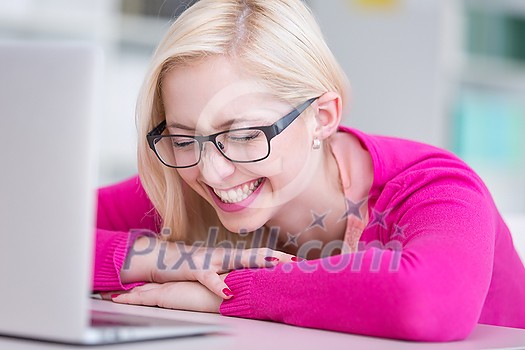 Pretty young college student in a library laughing in front of her laptop computer (shallow DOF; color toned image) Pretty young college student in a library laughing in front of her laptop computer (shallow DOF; color toned image)