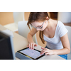 Smiling female student/ businesswoman using her tablet computer and a desktop computer, staying up to date, working, looking at the camera.