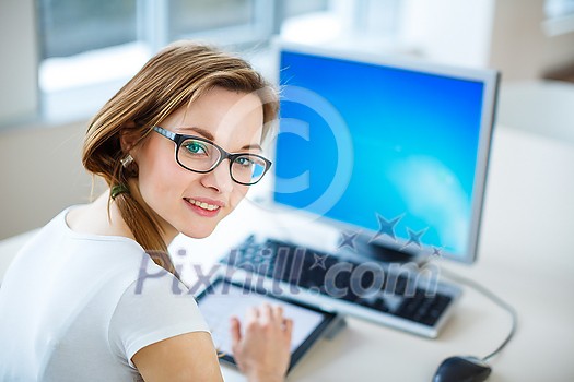 Smiling female student/ businesswoman using her tablet computer and a desktop computer, staying up to date, working, looking at the camera. Smiling female student/ businesswoman using her tablet computer and a desktop computer, staying up to date, working, looking at the camera.