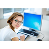 Smiling female student/ businesswoman using her tablet computer and a desktop computer, staying up to date, working, looking at the camera.