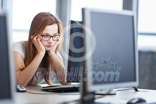 Pretty, female student looking at a desktop computer screen, learning unpleasant news about her exam results. University/office/school concept Pretty, female student looking at a desktop computer screen, learning unpleasant news about her exam results. University/office/school concept
