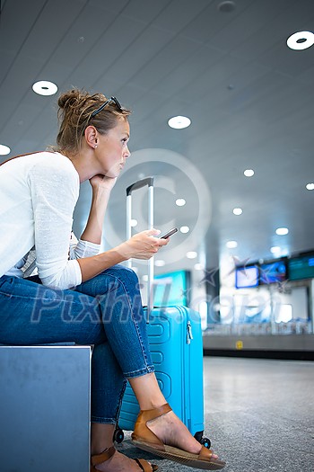 Young woman with her luggage at an international airport, before going through the check-in and the security check before her flight Young woman with her luggage at an international airport, before going through the check-in and the security check before her flight