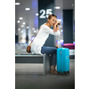 Young woman with her luggage at an international airport, waiting for her luggage to arrive at the baggage claim zone