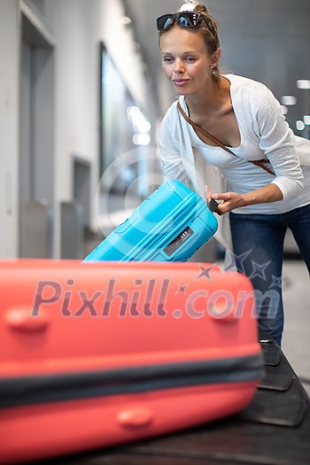 Young woman with her luggage at an international airport, waiting for her luggage to arrive at the baggage claim zone Young woman with her luggage at an international airport, waiting for her luggage to arrive at the baggage claim zone
