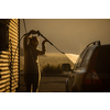 Cute woman washing her car in a manual carwash (color toned image)