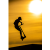Silhouette of a young  boy riding a scooter against the background of a sea sunset