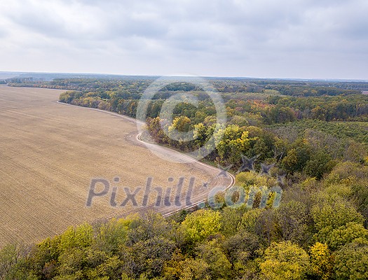 Aerial view from a drone above agricultural areas after harvesting with cultivated fields and autumn trees with yellow fallen leaves. Aerial view from a drone above agricultural areas after harvesting with cultivated fields and autumn trees with yellow fallen leaves.