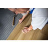 DIY, repair, building and home concept - close up of male hands lying parquet floor board/laminate flooring (shallow DOF; color toned image)