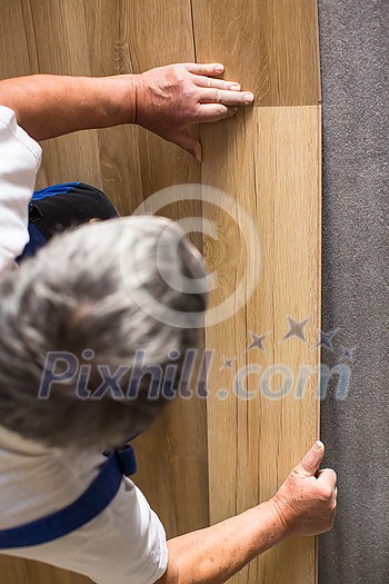 DIY, repair, building and home concept - close up of male hands lying parquet floor board/laminate flooring (shallow DOF; color toned image) DIY, repair, building and home concept - close up of male hands lying parquet floor board/laminate flooring (shallow DOF; color toned image)