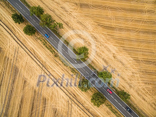 Aerial view of a country road amid fields with cars on it Aerial view of a country road amid fields with cars on it