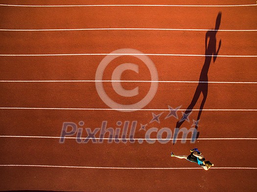 Shot of a young male athlete training on a race track. Sprinter running on athletics tracks seen from above Shot of a young male athlete training on a race track. Sprinter running on athletics tracks seen from above