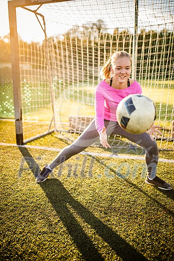 Teen female goalie catching a shot during a soccer game Teen female goalie catching a shot during a soccer game