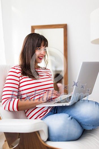 Successful young business woman sitting in a designer chair, working from home. Portrait of happy entrepreneur working on a laptop computer. Doing business remotely from the comfort of her home. Successful young business woman sitting in a designer chair, working from home. Portrait of happy entrepreneur working on a laptop computer. Doing business remotely from the comfort of her home.