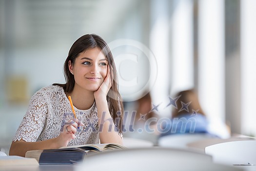 Pretty, young college student looking for a book in the library, studying for her exam Pretty, young college student looking for a book in the library, studying for her exam