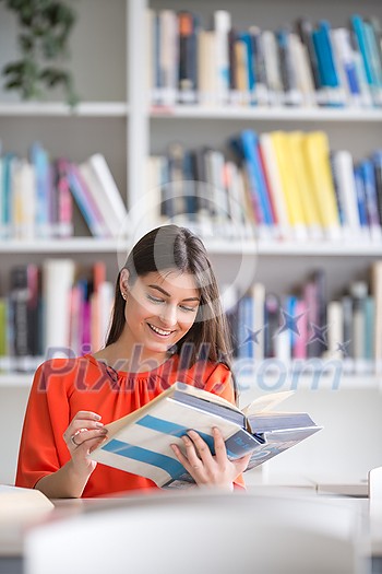 Pretty, young college student looking for a book in the library, studying for her exam Pretty, young college student looking for a book in the library, studying for her exam