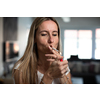Mid-aged woman lighting a cigarette at home, getting her nicotine daily dose, unable to resist to her unhealthy habit