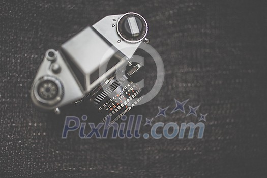 Old retro camera on vintage wooden boards abstract background with lens, close-up photo of old camera lens, image is retro filtered, selective focus