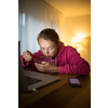 Bad habits concept - young woman paying attention to her smart phone while eating instead of being mindful while at the table