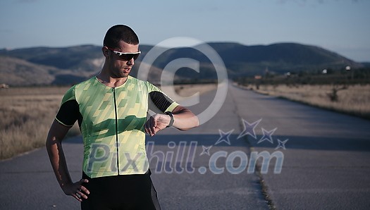 triathlon athlete running on morning training seting smartwatch while resting triathlon athlete running on morning training seting smartwatch while resting