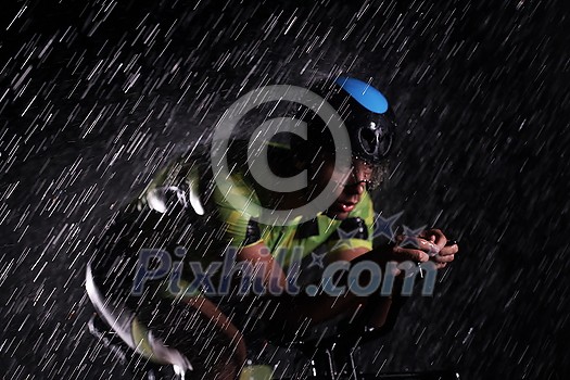 triathlon athlete riding professional racing bike fast at night with bad weather and falling rain triathlon athlete riding professional racing bike fast at night with bad weather and falling rain