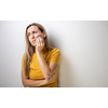 Mid-aged woman touching her cheek/mouth with painful expression because of toothache/dental issue