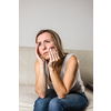 Mid-aged woman touching her cheek/mouth with painful expression because of toothache/dental issue