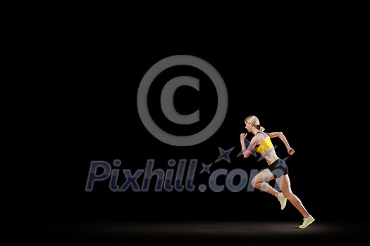 Young woman athlete running fast on dark background Young woman athlete running fast on dark background