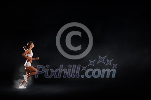 Young woman athlete running fast on dark background Young woman athlete running fast on dark background