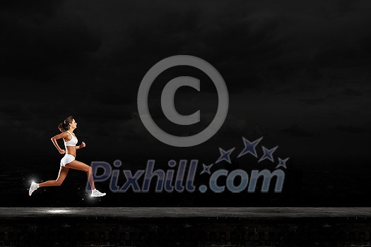 Young woman athlete running fast on dark background Young woman athlete running fast on dark background