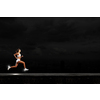 Young woman athlete running fast on dark background 