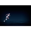 Young woman athlete running fast on dark background 