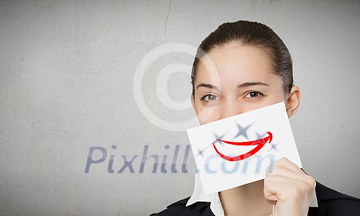 Pretty young girl holding white card with drawn smile